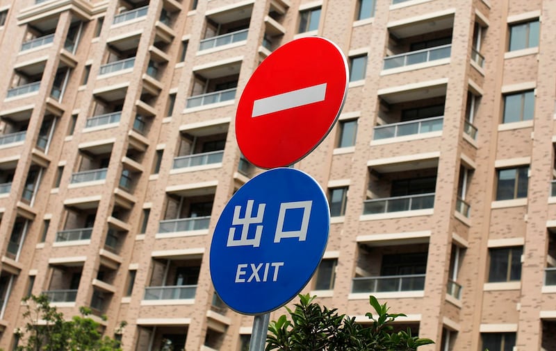 图为上海市一处住宅区的道路标志,背景中是无人入住的住宅楼。(路透社)