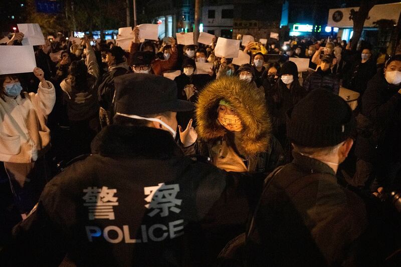 2022年11月27日,中国警察在北京与举着白纸的抗议者对峙。(美联社)