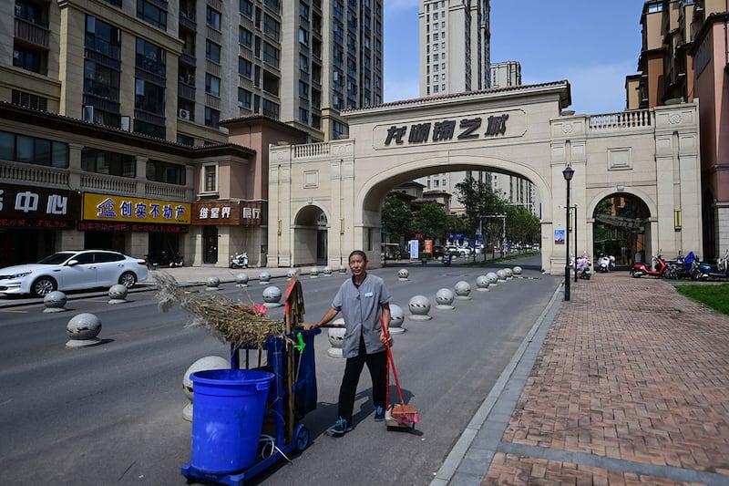 2023年6月20日,一名环卫工人站在河南省郑州市新郑市一栋未完工公寓楼入口前。(法新社)