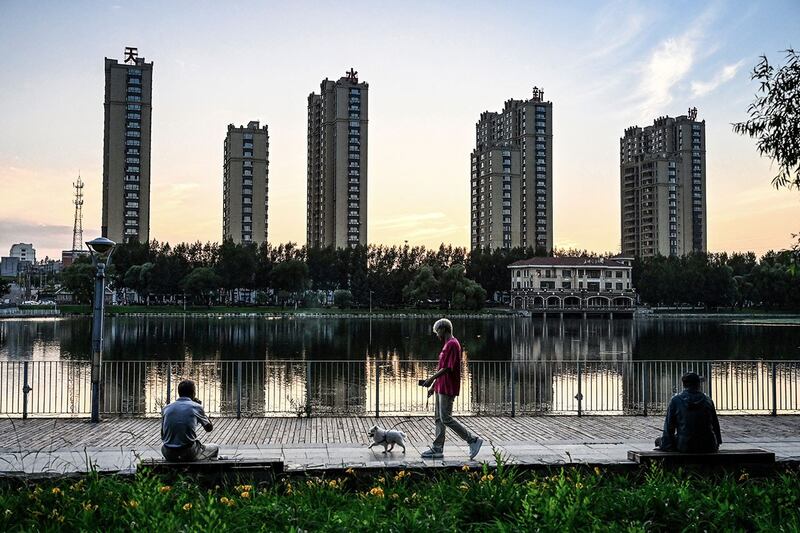 2023年7月4日,黑龙江省鹤岗市,人们在住宅楼附近的湖边休息。(法新社)