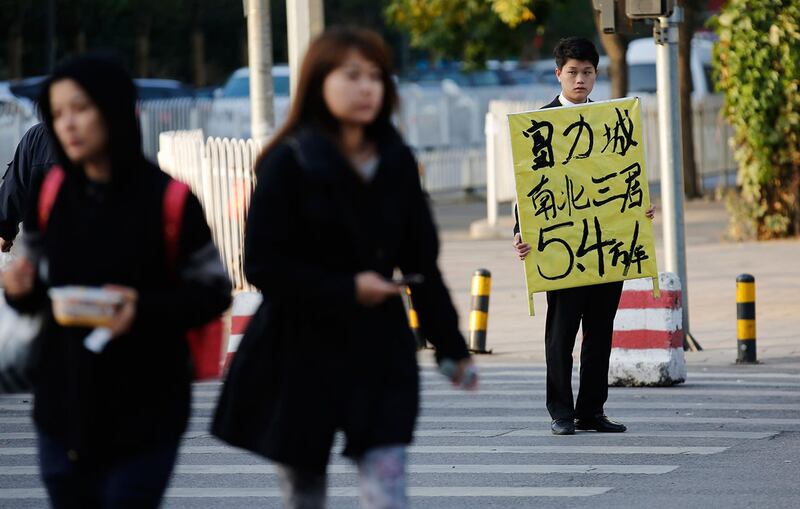 北京街道上,一名房地产经纪人(右)举着待售公寓的广告牌。(路透社)